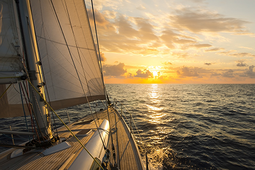 prow of sailboat sailing into sunset